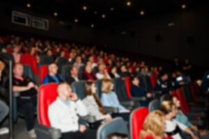 Publico sentado en una sala, visto en perspectiva y algo desenfocado